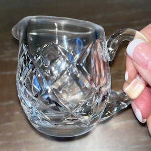 Peut inclure: Une cr&eacute;mier en verre transparent avec un motif en verre taill&eacute;. La cr&eacute;mier a une poign&eacute;e et un corps arrondi.
