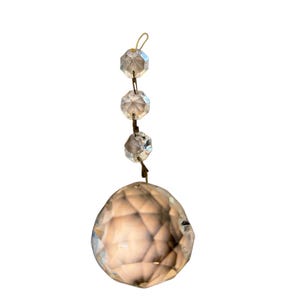 May include: A crystal prism with a large, faceted ball at the bottom and a chain of smaller faceted crystals above it.