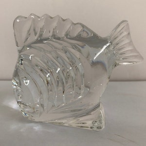 Peut inclure: Une sculpture de poisson en verre transparent avec un design textur&eacute; d&eacute;taill&eacute;. Le poisson est tourn&eacute; vers la droite et a un corps l&eacute;g&egrave;rement incurv&eacute;.