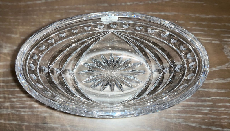 Puede incluir: Un plato ovalado de vidrio transparente con un patr&oacute;n de estrella en el centro y un borde festoneado. El plato est&aacute; vac&iacute;o.