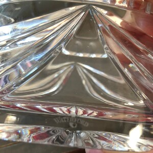 May include: Close-up of a clear glass bowl with a geometric pattern. The bowl has a Waterford logo on the bottom.
