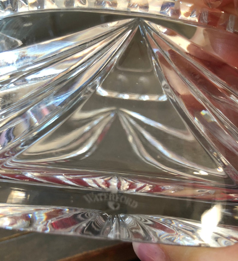May include: Close-up of a clear glass bowl with a geometric pattern. The bowl has a Waterford logo on the bottom.