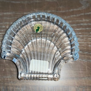 Puede incluir: Un plato de cristal transparente con forma de concha de mar con una etiqueta dorada que dice "Salem Crystal".