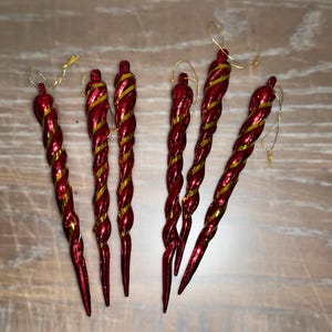 Puede incluir: Siete adornos de árbol de Navidad de vidrio rojo y dorado en espiral. Los adornos son de vidrio y tienen un acabado brillante.