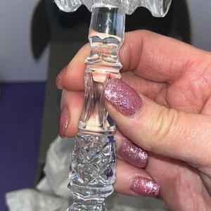 May include: A clear crystal gavel featuring intricate diamond-cut patterns on the head and handle. The head of the gavel displays a circular sticker with a seahorse emblem and the text Waterford Crystal. The piece has a faceted, reflective surface.