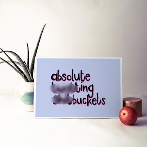 May include: A light blue card with the text "absolute hitting buckets" in black with pink outlines. The text is partially obscured by two gray ovals.
