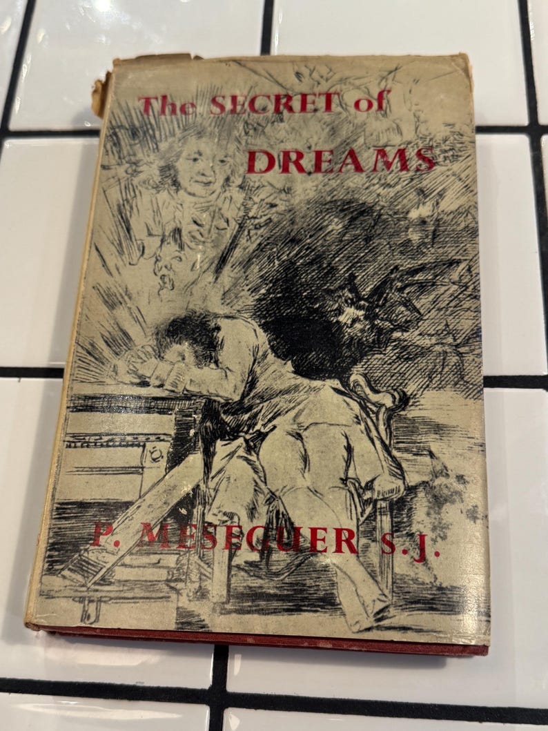 Puede incluir: Libro antiguo titulado "The Secret of Dreams" con una cubierta desgastada. La ilustraci&oacute;n de la portada muestra a una persona apoyada en una mesa, con otras figuras y texto rojo. El t&iacute;tulo del libro y el nombre del autor son visibles.