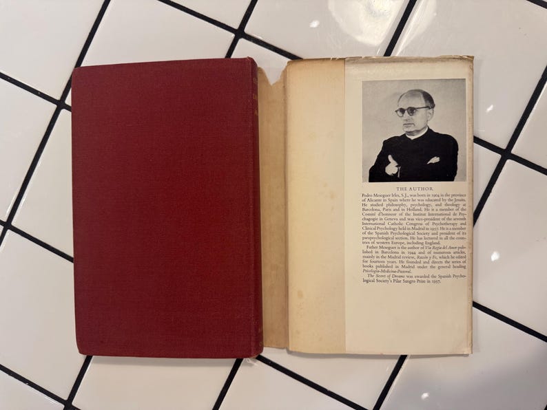 Puede incluir: Un libro abierto con una cubierta granate, que revela una p&aacute;gina con texto y un retrato en blanco y negro de un hombre con gafas. El texto incluye "THE AUTHOR" e informaci&oacute;n biogr&aacute;fica. El libro est&aacute; sobre una superficie de baldosas blancas.