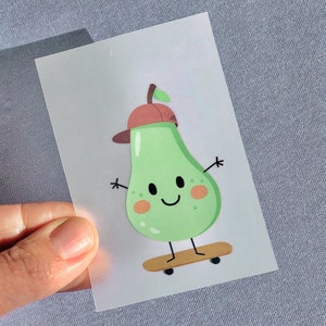 Könnte beinhalten: Eine grüne Birne mit einem rot-weißen Hut und einem lächelnden Gesicht steht auf einem Skateboard. Die Birne trägt einen rot-weißen Hut und hat ein lächelndes Gesicht. Die Birne steht auf einem Skateboard mit schwarzen Rädern.