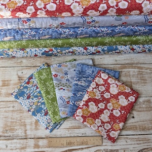 May include: A selection of Japanese-style fabric rolls and folded squares. The fabrics display floral, bamboo, and landscape designs in red, blue, green, and grey. A ruler with 'The Fabric Squirrel' is visible.