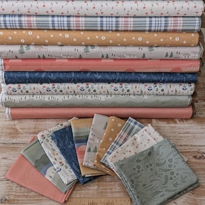 May include: A collection of folded fabric squares and stacked fabric bolts featuring various patterns including floral, plaid, and landscape designs in shades of sage green, dusty pink, navy blue, mustard yellow, and white, with a wooden ruler.