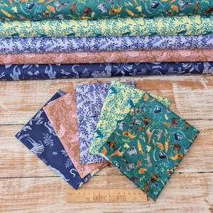 May include: Five folded fabric swatches in dark blue, pink, light blue, yellow, and teal, featuring animal and botanical prints. A wooden ruler labelled The Fabric Squirrel is placed at the bottom, showing a length of 15 centimetres.