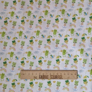 May include: White fabric with a repeating pattern of green frogs holding yellow umbrellas, rainbows, and yellow birds. The fabric is 15 inches wide.