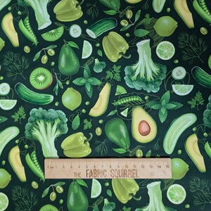 May include: A green fabric with a repeating pattern of various green vegetables, including avocados, broccoli, cucumbers, limes, kiwi, and peppers. The fabric is measured with a ruler that reads "THE FABRIC SQUIRREL".