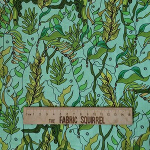Peut inclure: Un tissu vert menthe clair avec un motif répétitif d'algues, de varech et de petites bulles dans des tons vert foncé et olive. Une règle en bois est placée en bas, indiquant une échelle de mesure de 0 à 15 centimètres.