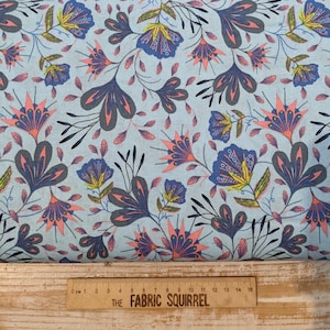 May include: A blue and white floral fabric with a repeating pattern of stylised flowers. The flowers are in shades of blue, pink, and yellow. The background is a light blue.