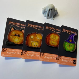May include: Four Halloween-themed acrylic pins featuring a black cat, a jack-o'-lantern with a skull, a jack-o'-lantern with a toothy grin, and a green pumpkin with a purple witch's hat. Each pin has the text "HALLOWEEN 2021 Acrylic Pin" and the Instagram handle "JosephGrzArt".