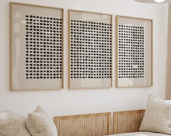 Puede incluir: Un sofá seccional beige claro con un marco de madera y tres impresiones de arte abstracto en blanco y negro colgadas en la pared detrás de él. Una mesa de café de madera con un pájaro de origami negro y un jarrón de flores rojas se encuentra frente al sofá.