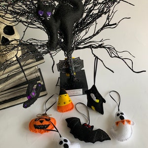 May include: A set of eight felt Halloween ornaments, including a black cat, a pumpkin, a ghost, a bat, a witch's hat, a candy corn, a ghost with "BOO" on it, and a black and yellow bat.