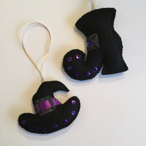 May include: Two felt Halloween ornaments, a black witch's hat with a purple ribbon and a black witch's boot with purple sequins.