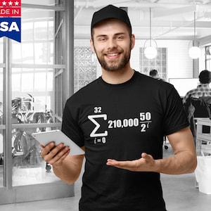 Puede incluir: Una camiseta negra con una ecuación matemática blanca impresa en la parte delantera. La ecuación es una sumatoria de i=0 a 32 de 210.000 dividido por 2 elevado a la potencia i. La camiseta la lleva puesta una persona en un entorno informal.
