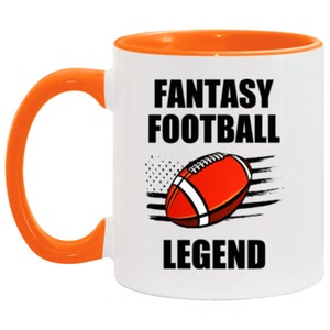 Puede incluir: Taza de café de cerámica blanca con borde y asa naranja. La taza presenta un gráfico en blanco y negro de un balón de fútbol con el texto "Fantasy Football Legend".