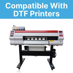 Pu&ograve; includere: Una stampante DTF di grande formato con corpo bianco e rosso, supporto nero e un rotolo di materiale bianco. La stampante ha pi&ugrave; cartucce d'inchiostro e il testo "Compatible With DTF Printers" in bianco su sfondo blu.