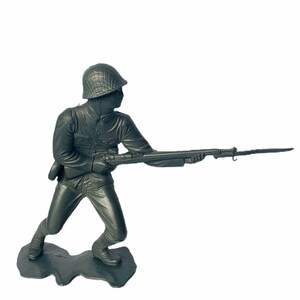Peut inclure: Une figurine de soldat en plastique gris tenant un fusil, debout sur une base grise. Le soldat porte un casque et est en position de tir.