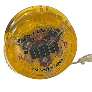 May include: A yellow plastic yo-yo with black lettering that reads "PRO. MEGA YO-YO PRO."
