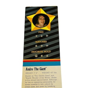 May include: A vintage wrestling trading card featuring Andre the Giant. The card has a yellow star with a photo of Andre in the center. The card lists his height as 7'4" and his weight as 477 lbs. The card also includes the text "PINS", "MATCHES", and "FAVORITE HOLD".