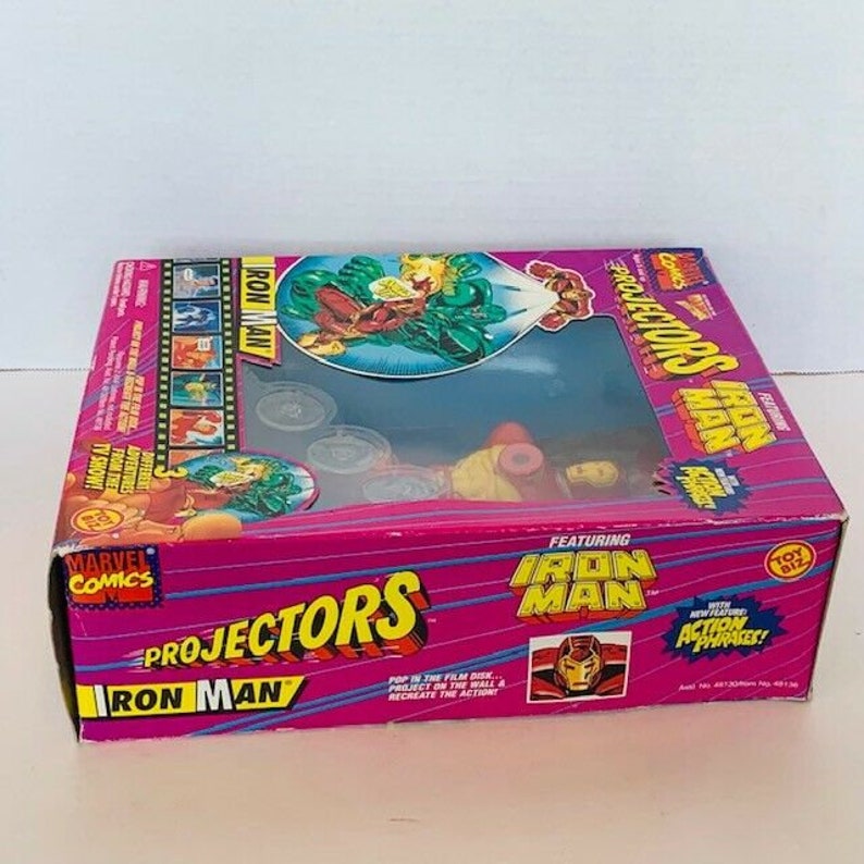K&ouml;nnte beinhalten: Eine pinkfarbene und rote Schachtel mit einem Bild von Iron Man auf der Vorderseite. Die Schachtel tr&auml;gt die Aufschrift "Projectors Iron Man" und "Featuring Iron Man". Die Schachtel ist f&uuml;r ein Spielzeug gedacht, das Bilder projiziert.