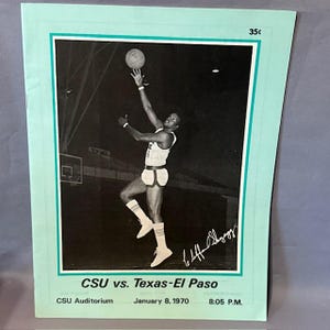 May include: Vintage black and white photograph of a basketball player in action, reaching for the ball. The image is framed with a light green border and includes text: "CSU vs. Texas-El Paso," along with the date and time of the game.