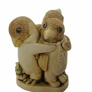 May include: A figurine of three penguins, two of them are hugging the third penguin who is wearing a tie. The penguins are made of a light brown ceramic material.