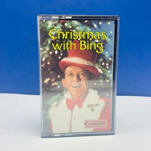 May include: A cassette tape featuring a picture of Bing Crosby dressed as Santa Claus. The tape is titled "Christmas with Bing".