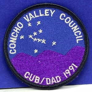 May include: A blue and purple embroidered patch with the text "Concho Valley Council Cub/Dad 1991" and a constellation of stars.