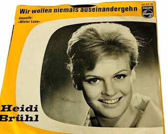 Puede incluir: Funda de disco de vinilo vintage con un retrato en blanco y negro de Heidi Brühl. La funda tiene detalles en amarillo y blanco y texto en alemán, incluyendo "Wir wollen niemals auseinandergehn" y "Mister Love."