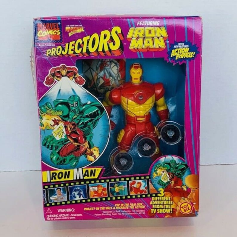 K&ouml;nnte beinhalten: Ein Marvel Comics Iron Man Projektorspielzeug mit einer roten und gelben Iron Man Figur mit einem roten und gelben Schild. Die Schachtel zeigt ein Comicbild von Iron Man und den Text "Projectors Iron Man" mit dem Slogan "Filmdisk einlegen, an die Wand projizieren und die Action nachspielen!"