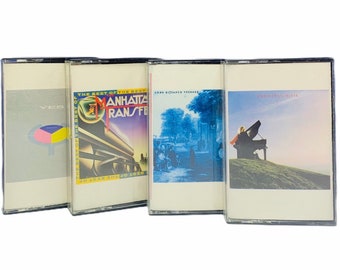 May include: Four cassette tapes with different album covers. The covers are: Yes, The Best of the Best of Manhattan Transfer, Long Distance Voyager, and Christine McVie.
