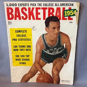 Può includere: Una copertina vintage della rivista Basketball del 1954 con un giocatore di basket in uniforme verde e bianca che palleggia un pallone da basket. Il titolo della rivista è in rosso e bianco, con testo che evidenzia le statistiche universitarie e professionali e le stelle delle scuole superiori.