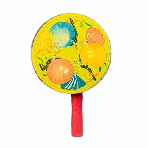 May include: A yellow toy tambourine with a red handle. The tambourine has a colorful illustration of people and balloons with the text "楽" on it.