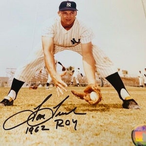 Puede incluir: Una fotografía en blanco y negro de un jugador de béisbol con un uniforme de los New York Yankees, recibiendo una pelota. El jugador lleva una gorra con el logotipo del equipo. La foto está firmada "Tom Tresh 1962 ROY".
