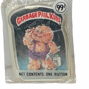 May include: A Garbage Pail Kids button featuring a character with orange skin and a purple jumpsuit. The character is holding a bottle of acne lotion and a toothbrush. The button is packaged in a clear plastic wrapper with a price tag of 99 cents. The text on the button reads "Garbage Pail Kids" and "Net Contents One Button."