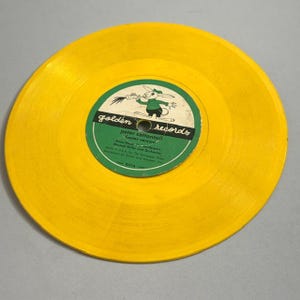 May include: A vintage yellow vinyl record with a green and white label. The label features a cartoon rabbit and the text "Peter Cottontail Easter Version." The record is a Golden Records release.