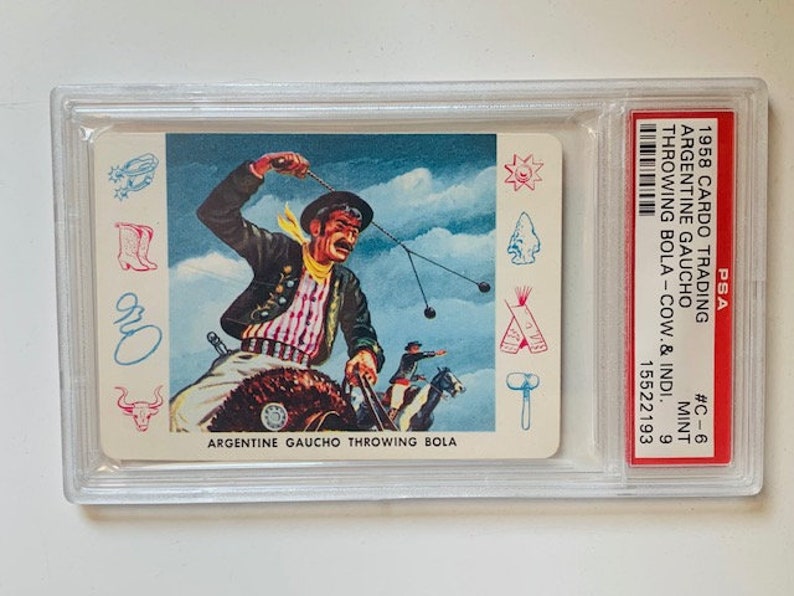Puede incluir: Una tarjeta de colecci&oacute;n vintage con una ilustraci&oacute;n colorida de un gaucho argentino lanzando una bola. La tarjeta est&aacute; calificada PSA 9 y tiene el texto "1958 CARDO TRADING ARGENTINE GAUCHO THROWING BOLA - COW & INDI. #C-6 MINT 9 15522193 ARGENTINE GAUCHO THROWING BOLA" impreso en ella.