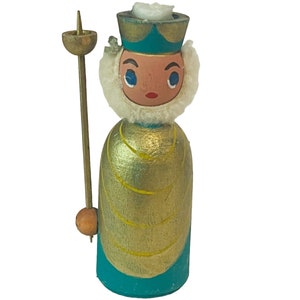 May include: A wooden figurine of a king with a gold and teal robe, a white fur collar, and a gold crown. He is holding a wooden staff with a gold top.
