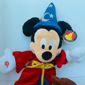 May include: A plush Mickey Mouse dressed as a wizard, wearing a blue hat with a crescent moon and star. He is wearing a red robe with a gold rope belt. The plush toy has a tag that says "Authentic Original Disney Theme Parks".