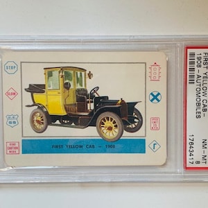 May include: A vintage 1958 Car-Do Trading card featuring a yellow 1908 First Yellow Cab automobile. The card is graded NM-MT 8 by PSA and has the number #A-21.