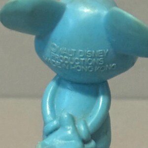Pu&ograve; includere: Una statuetta di plastica blu di un topo dei cartoni animati. La statuetta tiene le mani davanti al petto. La statuetta ha il testo "WALT DISNEY PRODUCTIONS MADE IN HONG KONG" stampato sul retro.