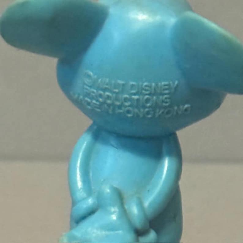 Pu&ograve; includere: Una statuetta di plastica blu di un topo dei cartoni animati. La statuetta tiene le mani davanti al petto. La statuetta ha il testo "WALT DISNEY PRODUCTIONS MADE IN HONG KONG" stampato sul retro.