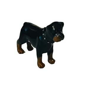 May include: Black and brown Rottweiler dog figurine. The figurine is made of ceramic and has a glossy finish.